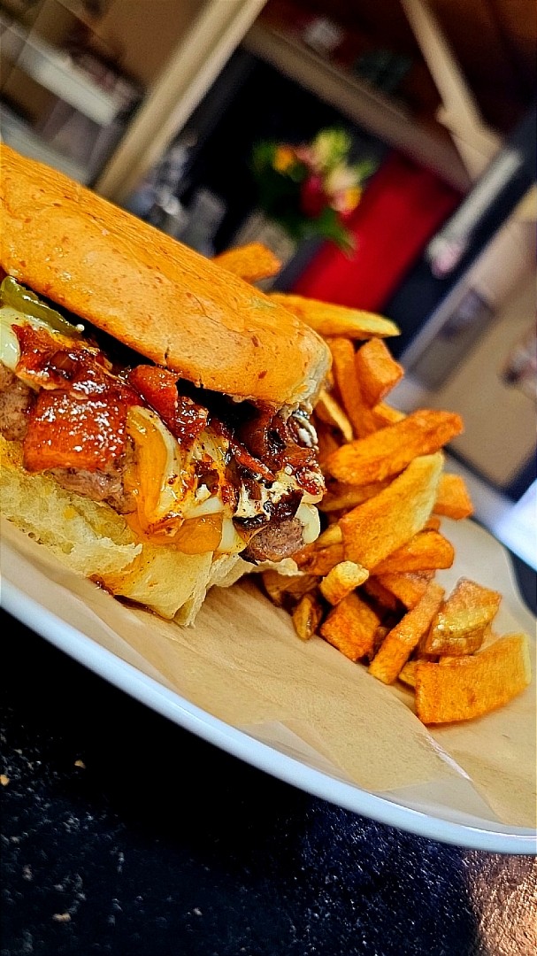 Grilled burger on a hoagie bun with hand-cut fries at Family Traditions Grill